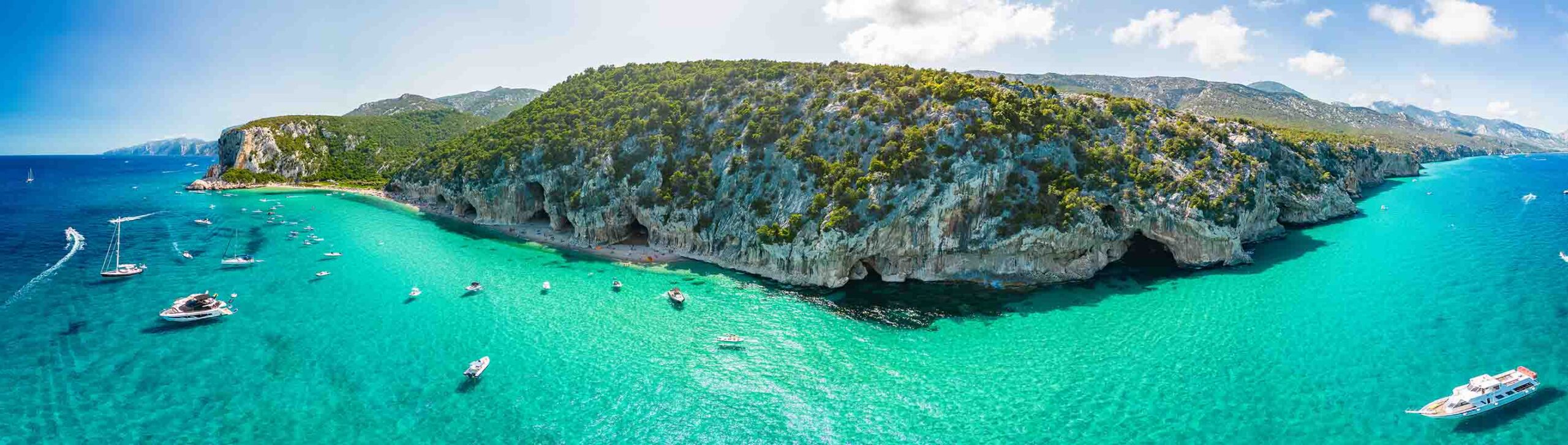 Spiaggia cristallina e scogliere verdi.